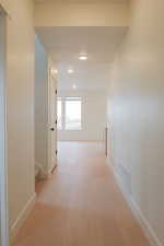 Hallway featuring light wood finished floors and baseboards