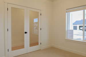 Unfurnished bedroom featuring carpet, french doors, and a closet