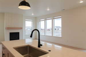 Kitchen with light wood-style floors, healthy amount of natural light, decorative light fixtures, light stone counters, and recessed lighting