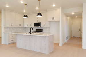 Kitchen with backsplash, hanging light fixtures, appliances with stainless steel finishes, recessed lighting, and light wood-style floors