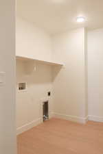 Laundry room featuring light wood-type flooring, washer hookup, and hookup for an electric dryer