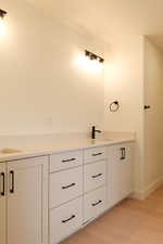 Full bath with double vanity and light wood-style flooring