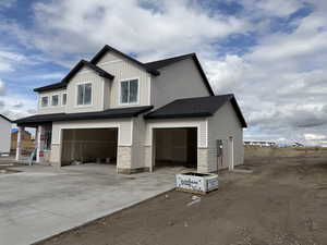 View of home's exterior featuring driveway, an attached garage, stone siding, board and batten siding, and a shingled roof