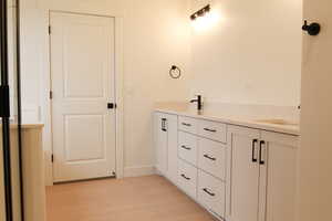 Full bath with double vanity and light wood-type flooring