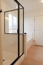 Bathroom with a stall shower, light wood-style flooring, recessed lighting, and a garden tub