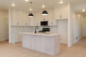 Kitchen with pendant lighting, appliances with stainless steel finishes, backsplash, recessed lighting, and a center island with sink