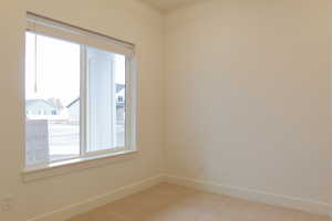 Empty room featuring baseboards and light colored carpet
