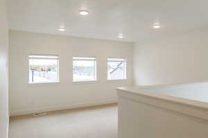 Empty room with light carpet and recessed lighting