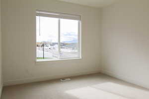 Unfurnished room with healthy amount of natural light, carpet floors, a residential view, and a mountain view