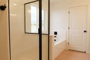 Full bath featuring a stall shower, a bath, and light wood-style flooring
