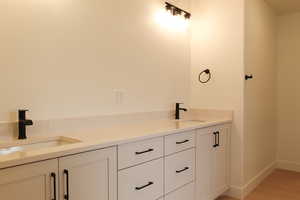 Full bathroom featuring double vanity and light wood-type flooring