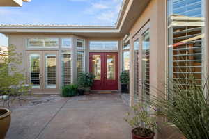 View of exterior entry with french doors, stucco siding, and a patio