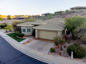 View of front of home featuring a garage, concrete driveway, a residential view, stucco siding, and a tile roof
