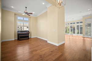 Spare room featuring ornamental molding, healthy amount of natural light, wood finished floors, a chandelier, and recessed lighting
