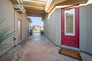 View of exterior entry with stucco siding and a gate