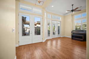 Doorway to outside with french doors, crown molding, hardwood / wood-style flooring, healthy amount of natural light, and a towering ceiling