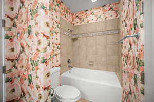 Bathroom with shower / bathtub combination with curtain and wallpapered walls