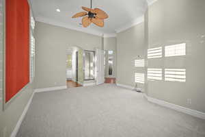 Spare room with light colored carpet, crown molding, arched walkways, and ceiling fan