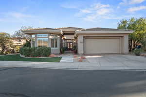 Prairie-style house with concrete driveway, an attached garage, stucco siding, a tiled roof, and a gate