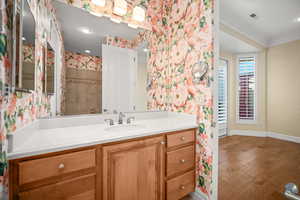 Bathroom featuring wallpapered walls, vanity, wood finished floors, crown molding, and recessed lighting
