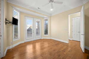 Empty room with french doors, ornamental molding, and wood finished floors