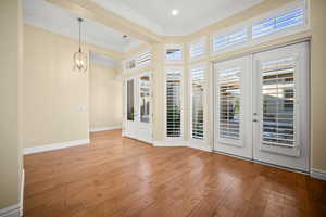 Unfurnished room with french doors, ornamental molding, wood-type flooring, and a chandelier