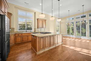 Kitchen with decorative backsplash, brown cabinetry, plenty of natural light, crown molding, and recessed lighting