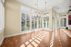 Unfurnished dining area featuring ornamental molding, wood finished floors, a chandelier, and a ceiling fan