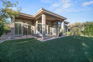 Back of property with a patio, a lawn, and stucco siding