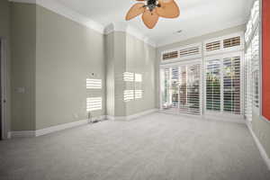 Spare room with ornamental molding, light carpet, and a ceiling fan