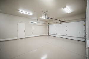 Garage featuring baseboards and a garage door opener