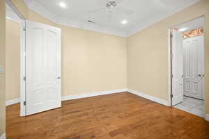 Unfurnished bedroom with wood finished floors, ornamental molding, a ceiling fan, and recessed lighting