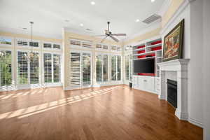 Unfurnished living room with ornamental molding, a glass covered fireplace, wood finished floors, recessed lighting, and a ceiling fan
