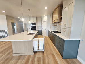 Kitchen with light wood-type flooring, a spacious island, decorative light fixtures, appliances with stainless steel finishes, and recessed lighting