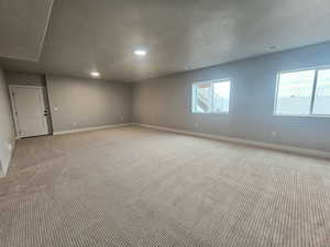 Carpeted empty room with a textured ceiling and recessed lighting