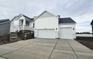 View of property exterior featuring board and batten siding, stone siding, a garage, and concrete driveway