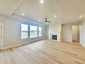 Unfurnished living room with recessed lighting, a glass covered fireplace, light wood-type flooring, a textured ceiling, and ceiling fan