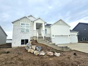 Craftsman-style home with board and batten siding, stone siding, and driveway