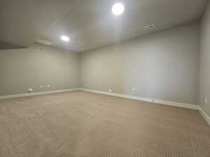 Below grade area with light carpet and recessed lighting