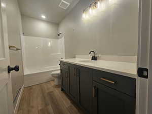 Bathroom featuring vanity, shower / bath combination, wood finished floors, and recessed lighting
