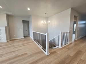 Corridor featuring an upstairs landing, light wood-style flooring, recessed lighting, and a chandelier