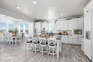 Kitchen featuring a breakfast bar area, healthy amount of natural light, paneled built in fridge, light wood-style flooring, and recessed lighting