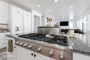 Kitchen with white cabinets, stainless steel gas stovetop, a textured ceiling, dark stone counters, and recessed lighting