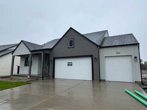 View of front of property with a shingled roof, driveway, stucco siding, and an attached garage