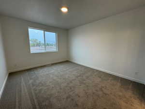 Carpeted spare room with baseboards