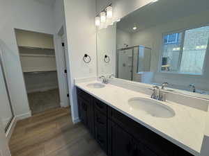 Bathroom with a stall shower, double vanity, light wood-style flooring, a spacious closet, and a bath