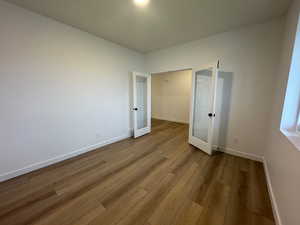 Unfurnished bedroom featuring french doors and wood finished floors