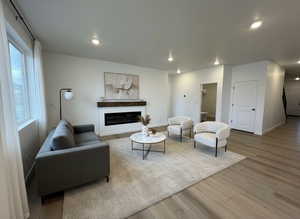 Living room with light wood-style flooring, a glass covered fireplace, and recessed lighting