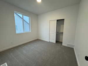 Unfurnished bedroom featuring dark carpet and a closet