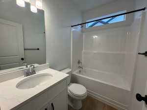 Bathroom with washtub / shower combination, vanity, dark wood-style flooring, and a skylight